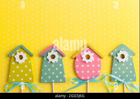 Colorful birdhouses on yellow polka dot background. Easter concept. Stock Photo