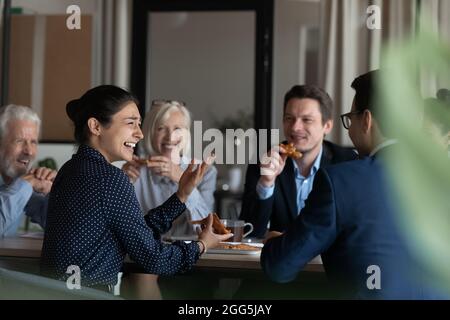 Excited diverse employees eating pizza during break in office together Stock Photo