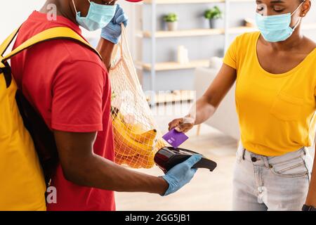 Female Paying Deliveryman For Groceries Using Credit Card Indoor, Cropped Stock Photo