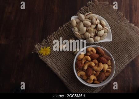 Mix nuts in bowls on wooden table. assorted nuts, pistachios, almonds, cashews, peanuts. diet and healthy eating concept Stock Photo