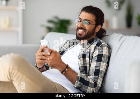 Handsome indian man playing games on smartphone at home Stock Photo