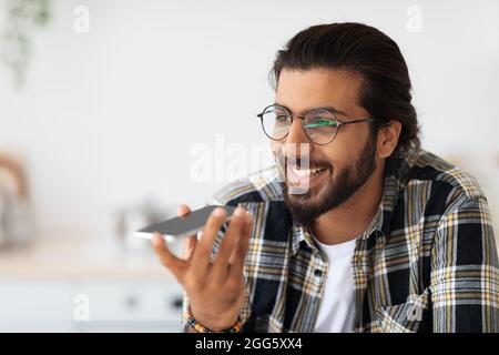 Handsome bearded arab man in glasses recording audio message Stock Photo