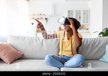 Millennial black woman using VR glasses at home Stock Photo