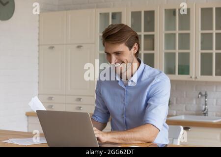 Happy young handsome businessman working on computer at home. Stock Photo