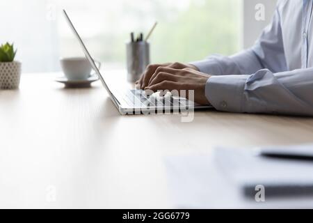 Hands of office employee typing on laptop keyboard at workplace Stock Photo