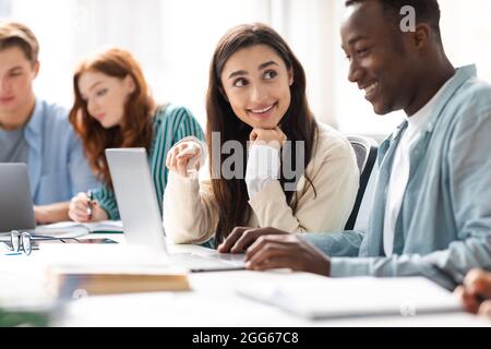Smiling diverse students sitting at desk working on group project Stock Photo