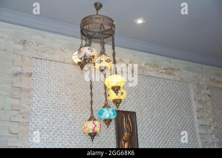 Colorful Turkish lamps and lanterns hanging in a lamp shop for sale. Decorative colorfull lights . Traditional Turkish lanterns made of colored glass Stock Photo
