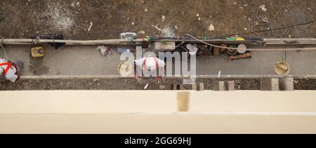 LAS PALMAS, SPAIN - AUGUST 13: Constriction workers on suspended platform repair a building facade,  construction being one of the very few well recov Stock Photo
