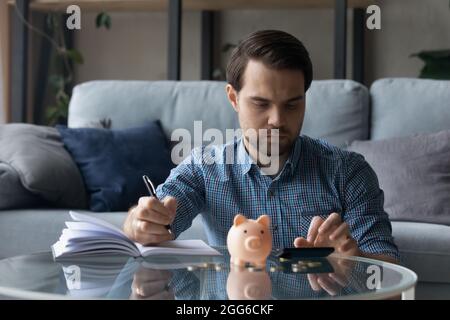 Serious millennial man calculating savings, counting budget Stock Photo