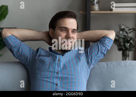 Thoughtful smiling guy relaxing on couch, looking away and smiling Stock Photo