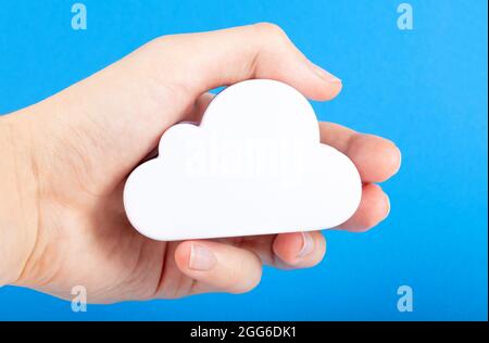 Hand holding a simple white cloud symbol, cloud computing technology metaphor, remote cloud data storage, meteorology and weather abstract concept. Cl Stock Photo