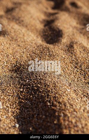 The texture of sand and small pebbles close up. Sun shadows, warm light Stock Photo
