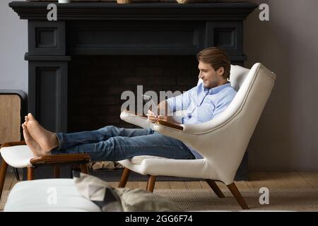 Relaxed young man using digital computer tablet. Stock Photo