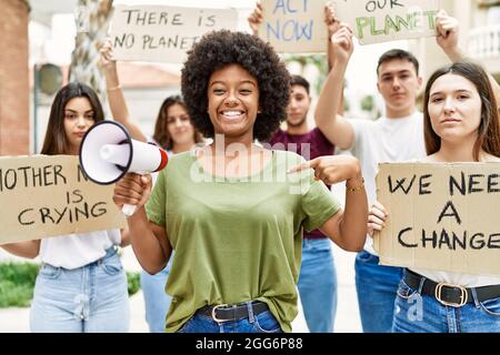 Group of young friends protesting and giving slogans at the street pointing finger to one self smiling happy and proud Stock Photo