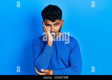 Arab man with beard wearing casual blue sweater thinking looking tired and bored with depression problems with crossed arms. Stock Photo