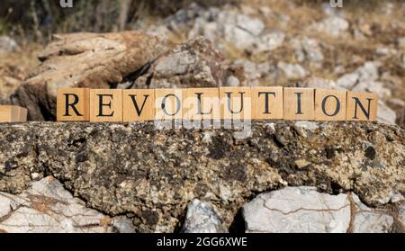 The word Revolution was created from wooden cubes. Photographed on the wall. Close-up. Stock Photo