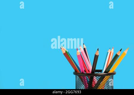 Office basket with colored pencils on blue background Stock Photo
