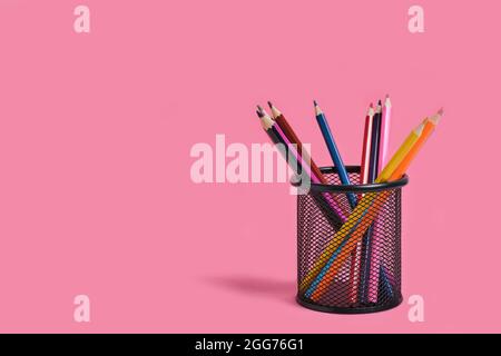Office basket with colored pencils on a pink background Stock Photo