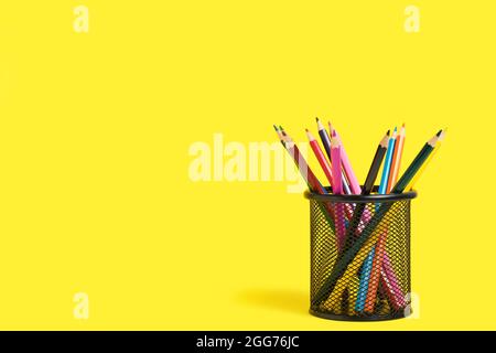 Office basket with colored pencils on yellow background Stock Photo