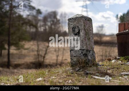 Concrete pole with black number 9 on a pole.  On a spring day, there is a metal pillar with a black inscription nine on the side of the slope Stock Photo