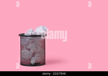 Crumpled paper in stationery wastebasket on pink background Stock Photo