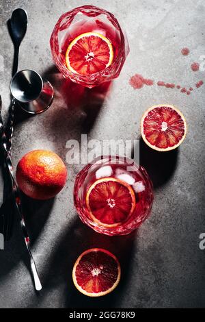 Negroni cocktail with ice cubes and blood orange on a dark  stone background, top view.