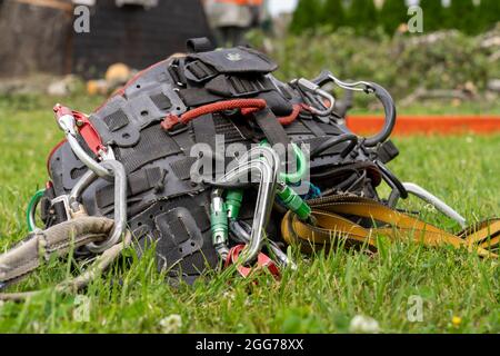 arborist climbing saddle dropped on the lawn  arborist climbing saddle with carbines, slings placed on the lawn Stock Photo