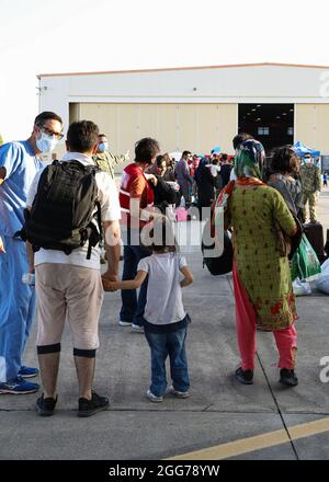 NAVAL AIR STATION SIGONELLA, Italy (Aug. 27, 2021) – U.S. Navy Sailors assigned to Navy Medicine Readiness and Training Command, U.S. military and Department of State personnel help evacuees from Afghanistan deplane a U.S. Air Force C-17 Globemaster III at Naval Air Station (NAS) Sigonella Aug. 27, 2021. NAS Sigonella is currently supporting the Department of State mission to facilitate the safe departure and relocation of U.S. citizens, Special Immigration Visa recipients, and vulnerable populations from Afghanistan. (U.S. Navy photo by Mass Communication Specialist 2nd Class Claire DuBois) Stock Photo