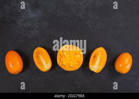 Ripe fresh yellow orange tomatoes on black background. Vegetables, healthy vegan organic food, harvest concept tomatoes layout cooking. sliced and whole tomatoes Stock Photo
