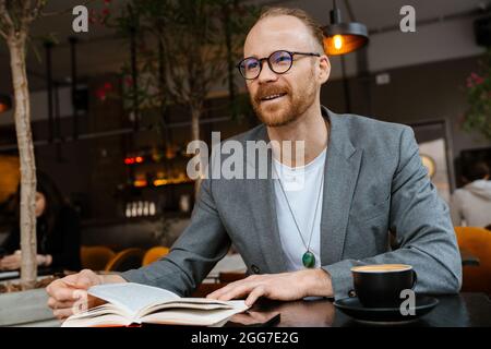 Confident middle aged white businessman working while sitting in the cafe indoors, writing Stock Photo