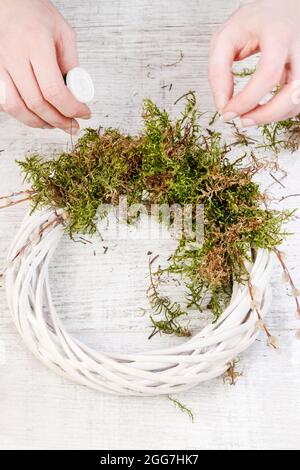 Florist at work: How to make white wicker wreath with moss, quail eggs and hyacinth flowers. Simple easter door decoration. Stock Photo