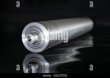 Steel metal pipe-shaft made on a lathe for the factory conveyor industry. Stock Photo