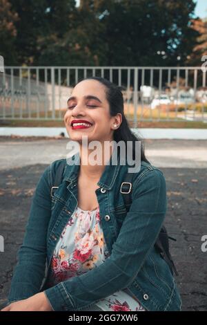 A vertical shot of a young Latin female sitting with a very happy face Stock Photo