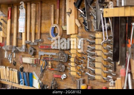 Various carpenter hand tools hanging on the wall in the carpentry workshop Stock Photo