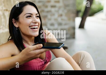 Young trendy woman sending voice message or recording audio sms on mobile phone Stock Photo