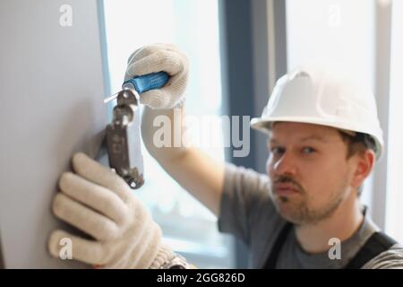 Man twists a screwdriver in a cabinet of fittings Stock Photo