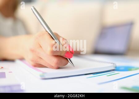 Womans hand taking notes with silver pen close-up Stock Photo