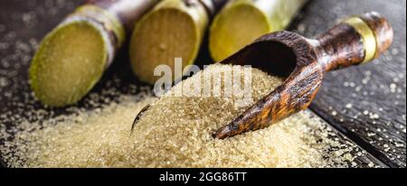 spoon with raw, brown sugar, with a wooden bottom and sugar cane Stock Photo