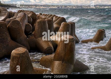 Concrete Tetrapods by recurved Sea Wall in Okinawa, Japan Stock Photo