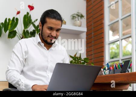 latino bearded man typing in the laptop in his legs Stock Photo