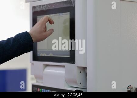 Engineer controls modern industrial equipment by touchscreen. Selective focus. Stock Photo