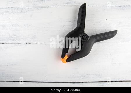 Black plastic clamp on a white wooden background. Stock Photo