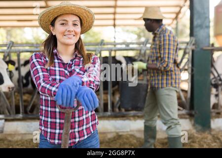 Portrait of a young positive laborer woman standing in the yard of a livestock farm Stock Photo