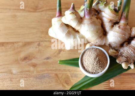 ginger powder in the bowl and fresh ginger on light wooden table, selected focus. top view Stock Photo