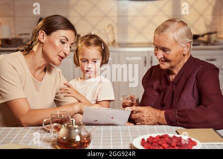 Mother and granny commenting on small child painting Stock Photo