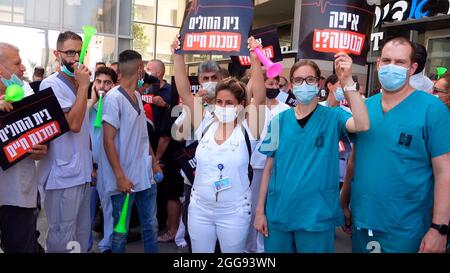 Doctors and medical staff protest against the lack of hospital funding from the Israeli government outside the Ministry of Health on August 29, 2021 in Jerusalem, Israel. Seven hospital directors said that due to the lack of funds, they will not admit new COVID-19 patients. Stock Photo