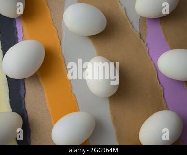 Eggs knolling, flat lay on colourful torn papers abstract texture background. Food styling, still life, fine art photography.