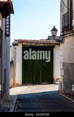 Green painted wooden doorway in the historic center of a village. Chinchon, Spain Stock Photo