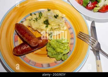 Traditional irish food with mashed potato, sausages and mushy peas  and fresh salad Stock Photo