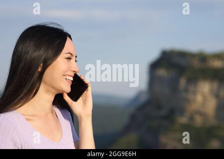 Asian woman talking on mobile phone smiling in the mountain Stock Photo